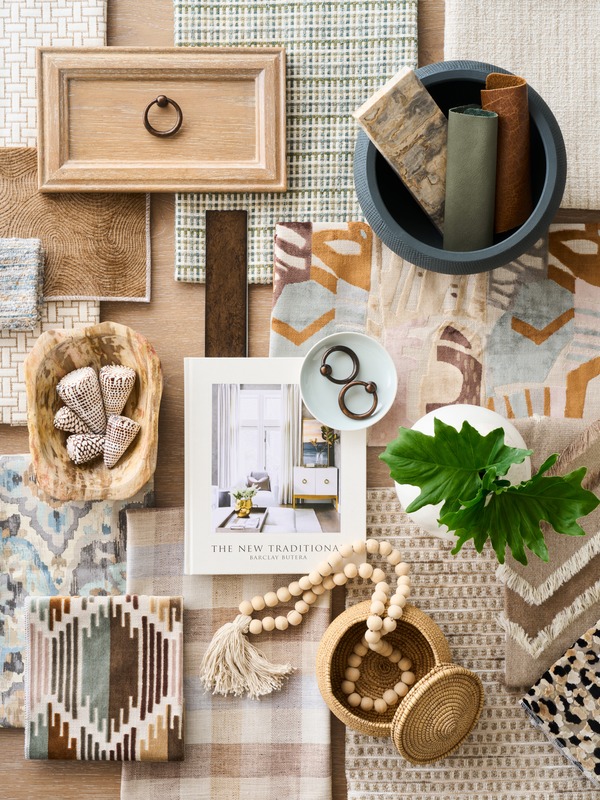 Interior design material samples, textiles, hardware, and greenery arranged on a table